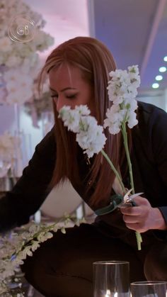 a woman sitting at a table with flowers in her hand and candles on the table