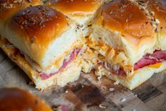 two ham and cheese sliders cut in half on top of a wooden cutting board