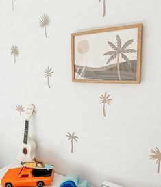 a toy car is sitting on top of a table in front of a wall with palm trees