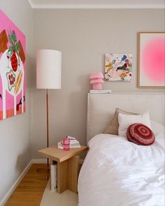 a white bed sitting in a bedroom next to a pink painting on the wall above it