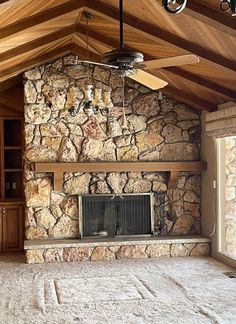 a living room with a stone fireplace and ceiling fan