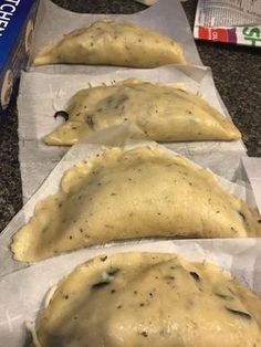 three uncooked pizza doughs sitting on top of wax paper lined up next to each other