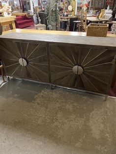 a large wooden cabinet sitting inside of a store next to chairs and other furniture in the background