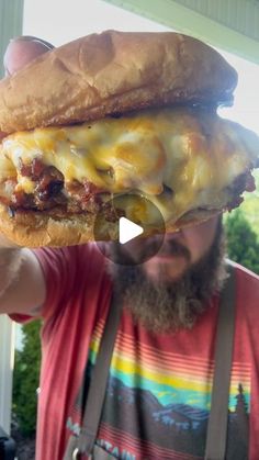 a man holding up a cheeseburger in front of his face