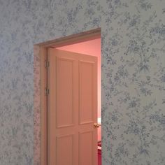 an open door leading to a bedroom with blue and pink wallpaper