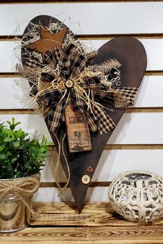 a heart shaped wooden sign sitting on top of a shelf next to a potted plant