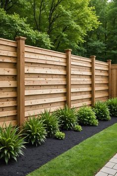 a wooden fence surrounded by green grass and plants on the side of a brick walkway