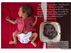 a baby laying on a red blanket next to a rock