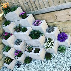 several cement planters stacked on top of each other with flowers growing out of them