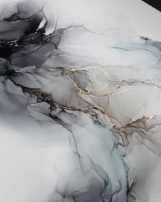 an abstract marble table top with gold and black designs on the edges, in grey tones