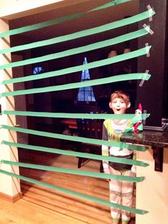 a young boy standing in front of a window with green streamers on the side