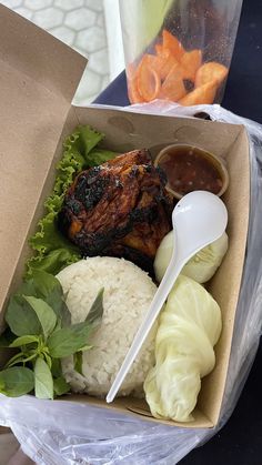 a meal in a box with meat, rice and lettuce on the side