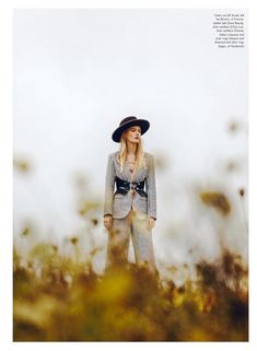 a woman wearing a hat standing in tall grass