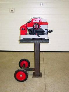 a red and black machine sitting on top of a metal stand next to a white wall