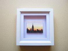 a white frame hanging on the wall with a cityscape in it