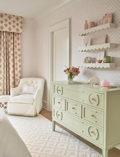 a bedroom with pink and white wallpaper, green dresser and chair in the corner