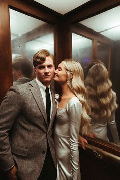 a man and woman standing next to each other in front of a mirror with long blonde hair