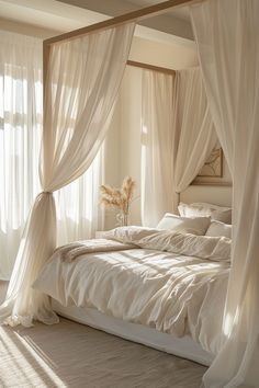 a bed with white sheets and drapes in a bedroom next to a large window