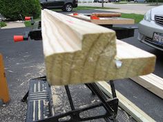 a piece of wood sitting on top of a wooden bench in front of a car