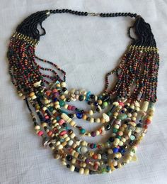 "Multi-color bead statement necklace with a tribal African flair. Lots of different shapes and colors, including a few tiny shells. About 18\" long, hangs about 4\" deep on your chest. Also, please take a look at my storefront at: https://www.etsy.com/shop/FabFinds42?ref=seller-platform-mcnav I have a wide selection of one-of-a-kind items, from clothing and toys to home decor and gift items, and I add new things almost every day." Multicolor Wooden Beads For Festival, Bohemian Beaded Necklaces For Beach With Polished Beads, Multi-strand Wooden Beads For Jewelry Making, Bohemian Multicolor Heishi Beads, Wooden Multi-strand Beads For Jewelry Making, Artisan Multicolor Multi-strand Beaded Necklaces, Artisan Multicolor Beaded Chain Necklace, Artisan Multicolor Beaded Necklace For Beach, Artisan Multicolor Multi-strand Beads