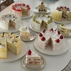 many different types of cakes on plates on a table