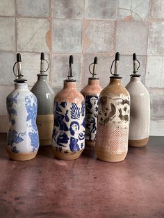 five different colored vases sitting on top of a table next to a brick wall