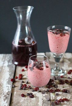 two glasses filled with cranberry and chocolate pudding on top of a wooden table