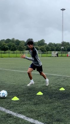 a young man is playing soccer on the field with yellow cones in front of him