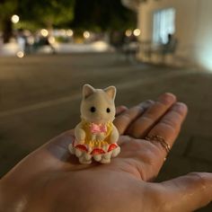 a tiny toy cat sitting on top of someone's hand in the street at night