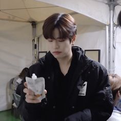 a young man is looking at his cell phone while standing in front of a tent