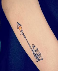 a person with a small tattoo on their arm holding a lamp post and looking at the ground