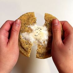 two hands holding crackers in front of each other on a white surface with black sprinkles