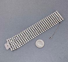 "This sparkling clear stone bracelet is such a beauty. It is silver (base metal silver/white metal) with a rhodium plate, and dates probably from the 1950s. It is beautiful clear rhinestones, 8 rows wide. Simple style, yet very elegant and gorgeous! Marked: Unsigned.... maybe Kramer or Weiss? Measurements: 7\" x 1.38\" wide. Fastens with a push in box clasp. Condition: Beautiful vintage condition. Stones are brilliant and sparkly. They are NOT dark or yellow like it may appear in some of the pic Silver Rhinestone Crystal Bracelet Costume Jewelry, Silver Rhinestone Costume Jewelry Bracelet, Silver Costume Jewelry Bracelets With Rhinestones, Silver Rhinestone Bracelet In Costume Jewelry Style, Silver Rhinestone Bracelet For Costume Jewelry, Formal Silver Crystal Bracelet With Rhinestones, Silver Crystal Bracelet With Rhinestones For Formal Occasions, Silver Bling Crystal Round Bracelet, Silver Sparkling Round Diamond Bracelet