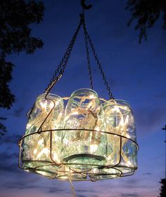 a glass jar chandelier with lights hanging from it's sides at night