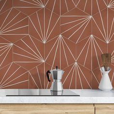 a kitchen counter with a coffee pot and pitcher on it, next to a tile wall