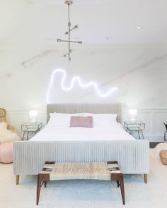 a bedroom with a large bed in the middle and a neon sign above it on the wall