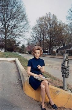 a woman sitting on the curb reading a book