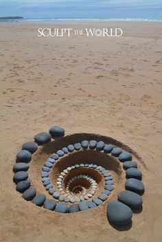 a spiral made out of rocks on the beach with text saying sculpt the world