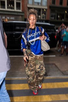 a woman with dreadlocks walking across a street