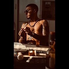 a man with tattoos sitting at a table in front of some bottles and spoons