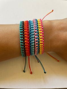 a person's arm with several different colored bracelets on top of each other