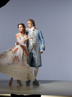 a man and woman dressed in costume standing next to each other on a white floor