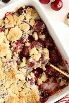 a cherry cobbler in a white dish with a gold spoon