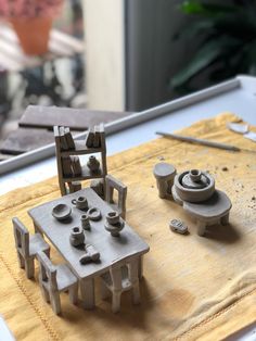 a wooden table topped with miniature pieces of art and crafting equipment on top of a piece of cloth