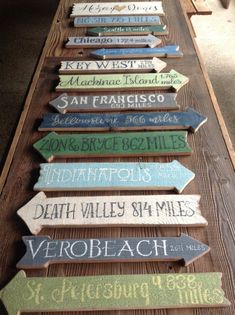 several wooden signs are lined up on a long table with the names of different towns