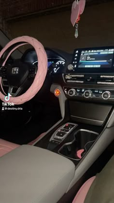 the interior of a car with pink leather seats and steering wheel cover, including an electronic display