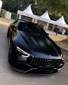 a black sports car parked in front of a white tent on the side of a road