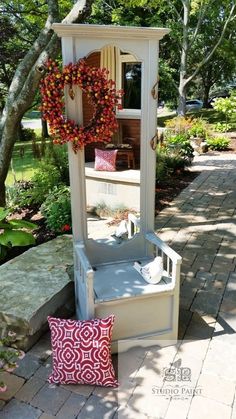 an outdoor bench with a wreath on it and a mirror in the corner next to it