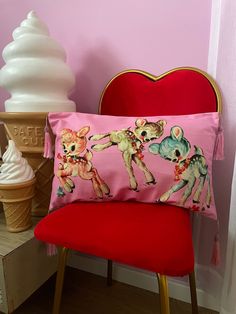 a pink pillow sitting on top of a red chair next to an ice cream cone