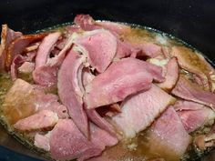 ham is cooking in a pan on the stove top, ready to be put into the slow cooker